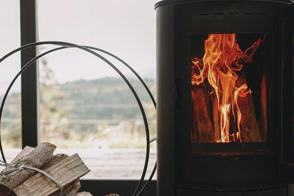 Wood burning in stove in home next to log holder